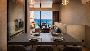A dining area with a table set for four, a hanging chair, and a view of the ocean. - nagisa awajishima (Awaji)