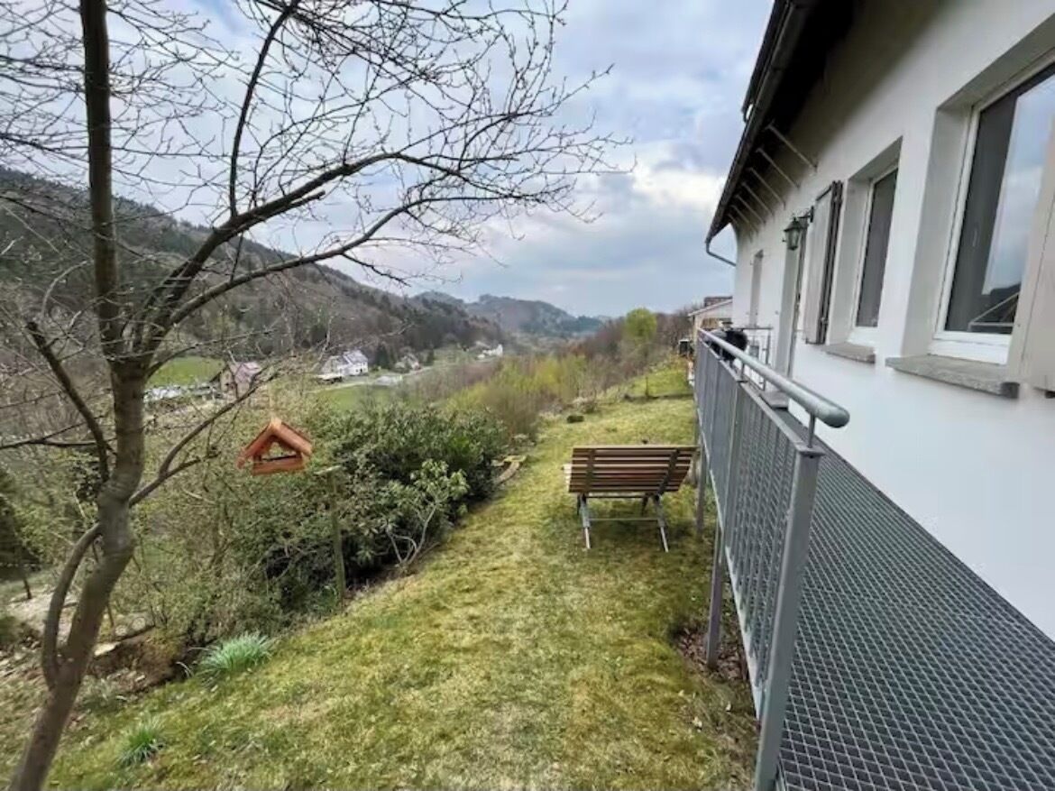 Un balcon doté d’une rambarde en métal, d’un banc et d’une mangeoire à oiseaux.