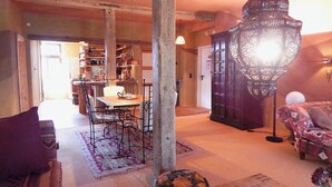 A spacious living area with a dining table, chairs, a sofa, and a hanging light fixture. - Morgenland - vacation apartment for those who want more than just a place to stay (Fürstenberg/Havel)