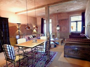 Ein Essbereich mit Holztisch und Stühlen, einer Couch, einem kleinen Couchtisch und einem gemusterten Teppich.