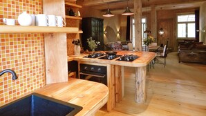 A kitchen with wooden shelves, a built-in stove, and a dining area with a sofa and table. - Morgenland - vacation apartment for those who want more than just a place to stay (Fürstenberg/Havel)