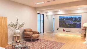 A modern living room with a flat-screen TV, a glass coffee table, a patterned rug, and a comfortable armchair. - Stylish Homestay Balcony View Bell Tower (Xi'an)