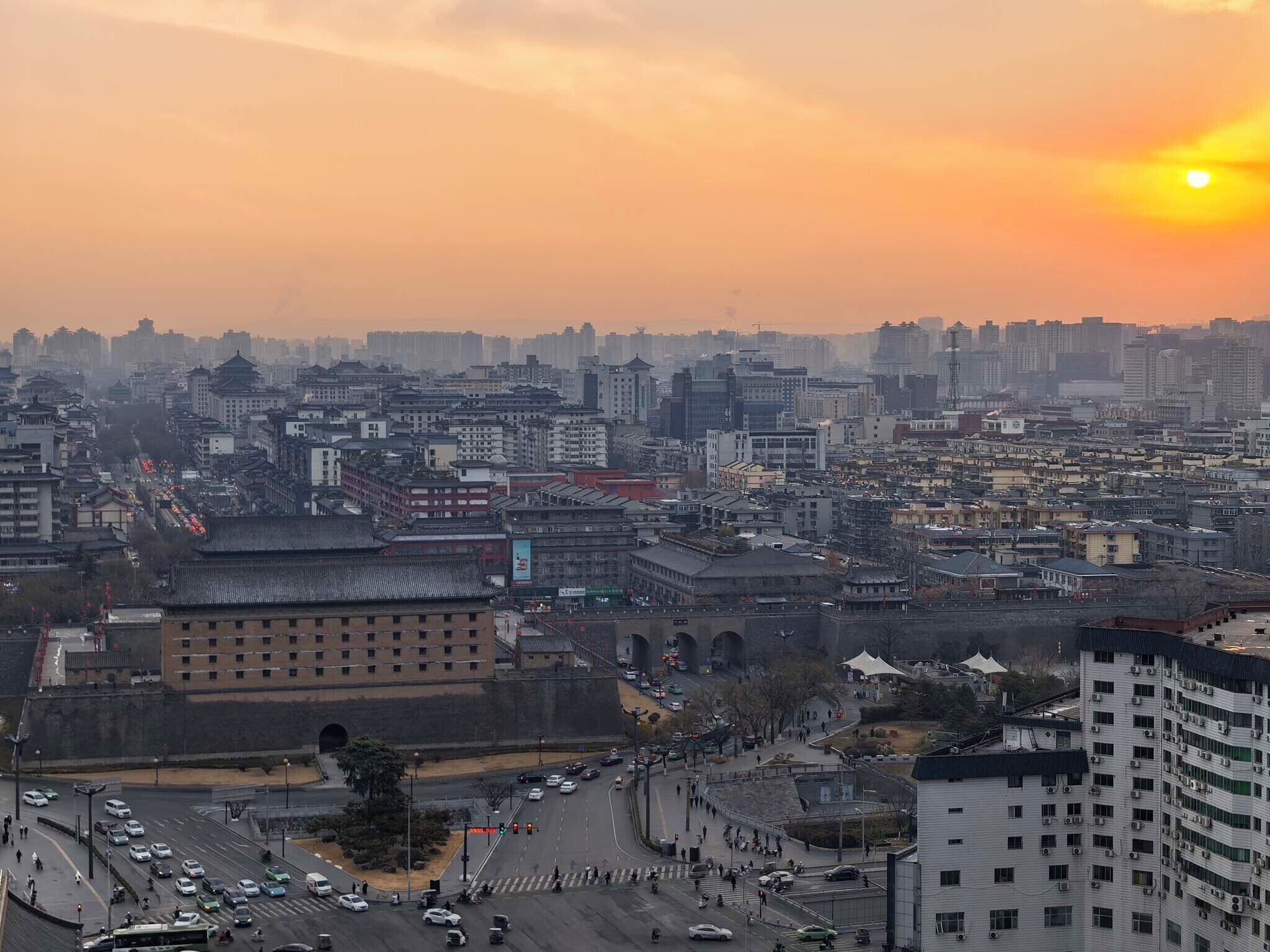 Une vue urbaine comprenant des bâtiments traditionnels et modernes, un carrefour animé et un ciel dégagé.