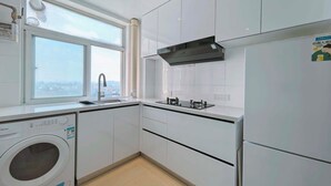 A modern kitchen with a built-in washer, a window with a city view, and a black range hood. - Stylish Homestay Balcony View Bell Tower (Xi'an)