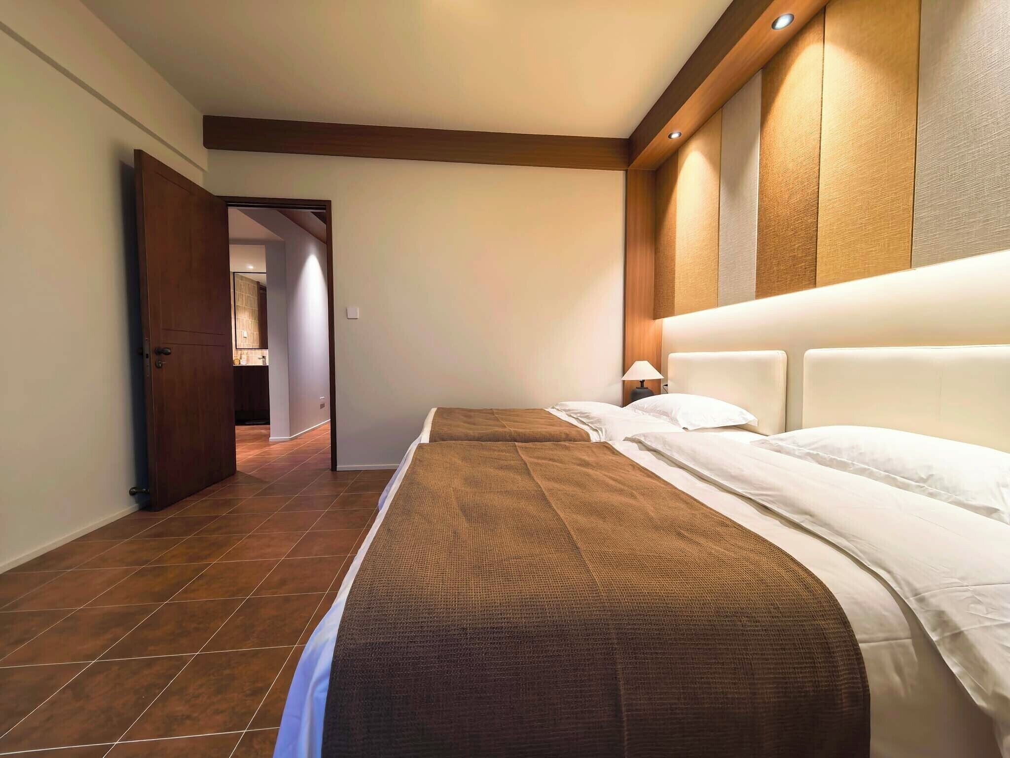 A hotel room with a bed, a nightstand, a lamp, and a wooden headboard.