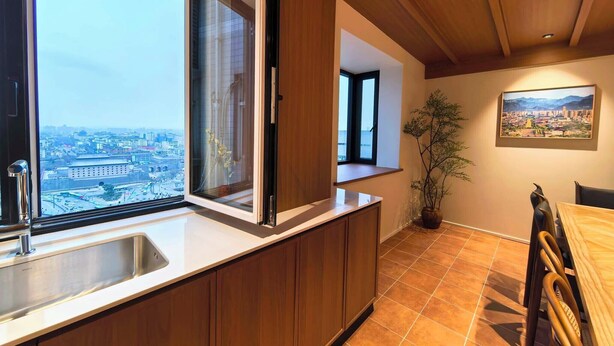 A kitchen with a large window, wooden cabinets, a sink, and a dining area with chairs. - Stylish Homestay Balcony View Bell Tower (Xi'an)