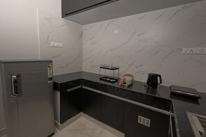 A modern kitchen with a refrigerator, a coffee maker, and a small shelf with items. - 3-bedroom Premium Serviced Apt right in front of Vaigai River, Kochadai, Madurai (Madurai)