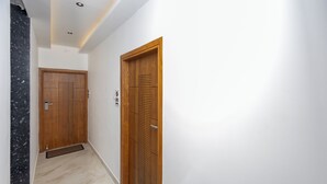 A hallway with two wooden doors, a marble wall, and a tiled floor. - 3-bedroom Premium Serviced Apt right in front of Vaigai River, Kochadai, Madurai (Madurai)