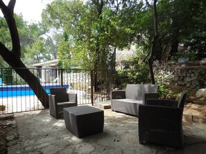 An outdoor patio with wicker furniture, a stone wall, and a pool in the background. - Magnificent property close to beaches and Montpellier (Cournonsec)
