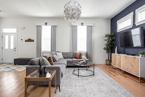 A modern living room with a sofa, coffee table, and TV. - Spacious retreat w/ theater & rooftop deck (Indianapolis)