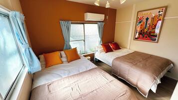 Een hotelkamer met twee bedden, een raam met gordijnen, een airconditioning en een poster aan de muur.