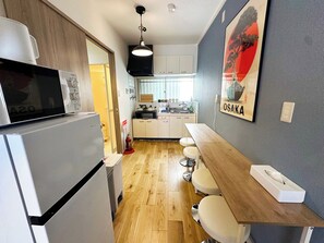 A compact kitchen with a microwave, stove, and wooden bar seating. - Open Sale / 3 min. walk to station / Close to UFJ / Direct access to Namba / Easy access to Kobe and Nara / Detached house (大阪市)