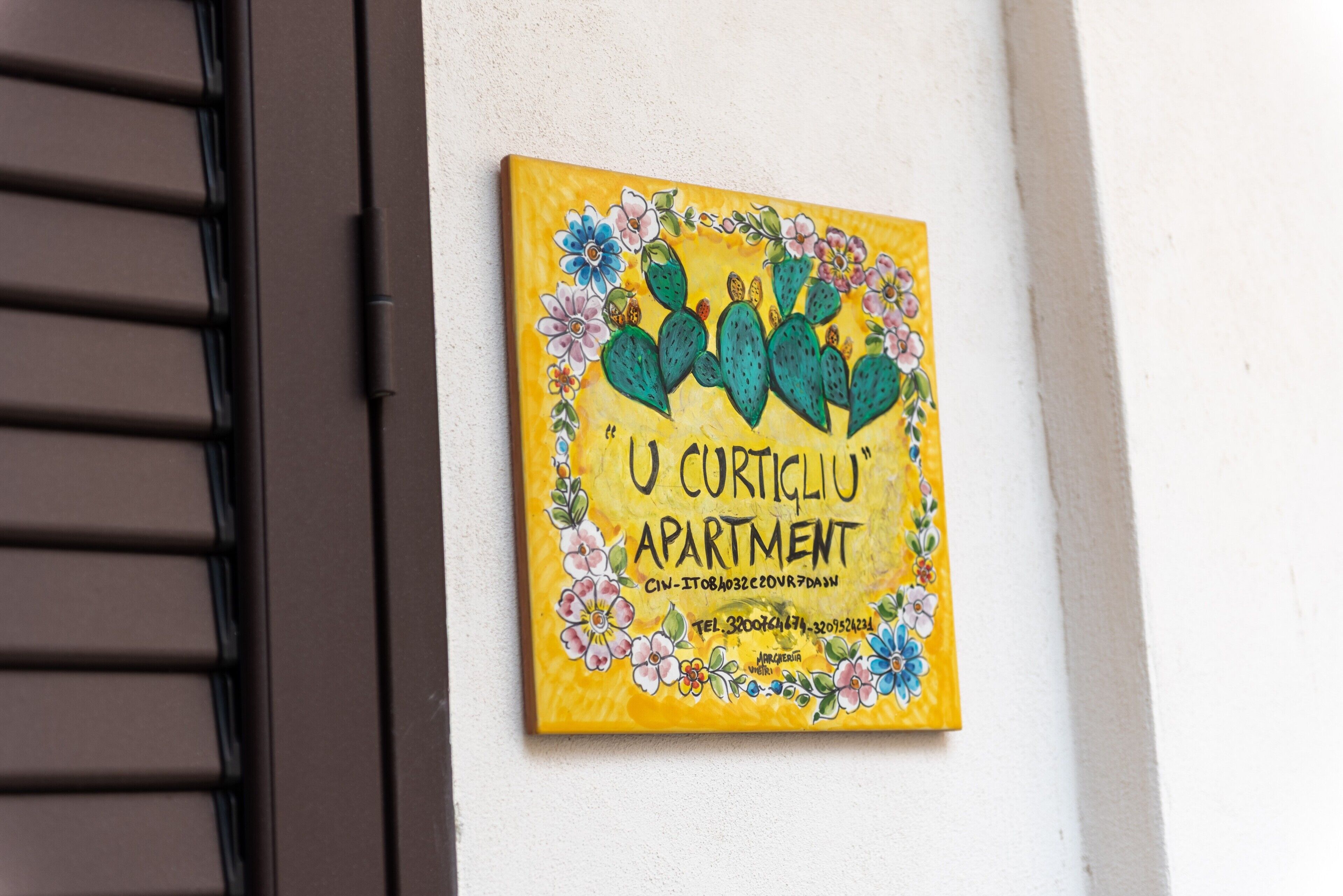 A wall-mounted sign with a floral design and text indicating 'U CURTICLU' APARTMENT.