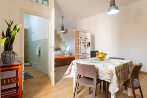 A room with a bed, a table with chairs, a bookshelf, and a potted plant. - Apartment 'U Curtigliu -' with Shared Terrace, Wi-Fi and Air Conditioning (Realmonte)