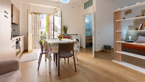 A modern kitchen with wooden cabinets, a dining table with a floral tablecloth, and a hanging light fixture. - Apartment 'U Curtigliu -' with Shared Terrace, Wi-Fi and Air Conditioning (Realmonte)