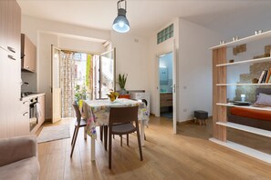 A modern kitchen with wooden cabinets, a dining table with a floral tablecloth, and a hanging light fixture. - Apartment 'U Curtigliu -' with Shared Terrace, Wi-Fi and Air Conditioning (Realmonte)