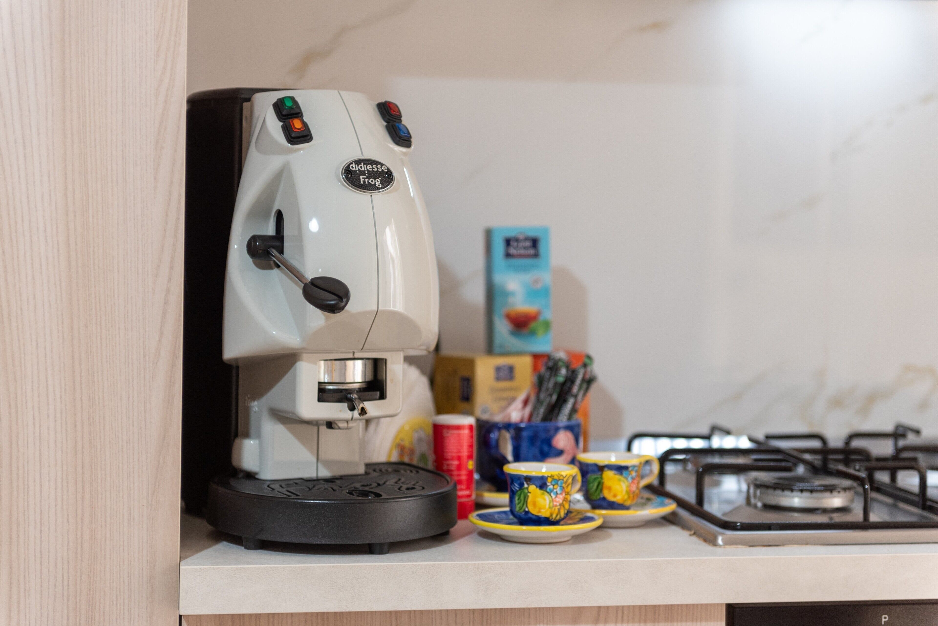 A coffee machine with a control panel, a gas stove, and a cup holder with mugs.