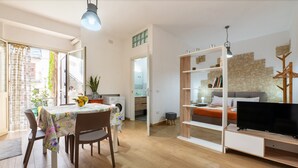 A modern living room with a dining area, a television, and a stone wall. - Apartment 'U Curtigliu -' with Shared Terrace, Wi-Fi and Air Conditioning (Realmonte)