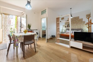 A modern living room with a dining area, a television, and a stone wall. - Apartment 'U Curtigliu -' with Shared Terrace, Wi-Fi and Air Conditioning (Realmonte)