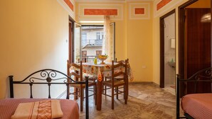 A hotel room with a bed, a dining table with chairs, a bathroom visible through an open door, and a balcony with a railing. - Family Room in Realmonte near Scala dei Turchi with Private Balcony (Realmonte)