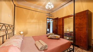 A room with a bed, a wooden wardrobe, a mirror, and a ceiling light fixture. - Family Room in Realmonte near Scala dei Turchi with Private Balcony (Realmonte)