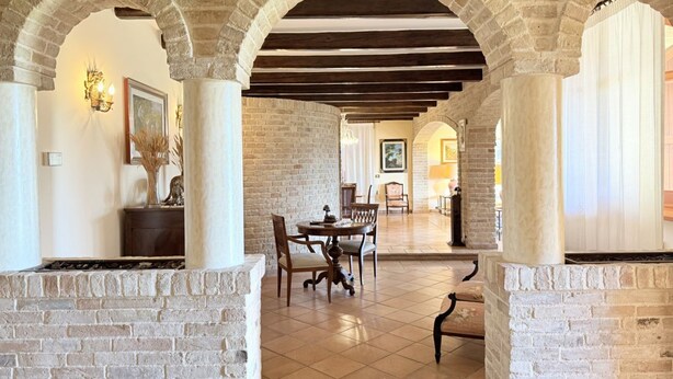 A spacious interior with stone arches, a dining area with a table and chairs, and a fireplace.