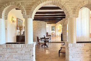 A spacious interior with stone arches, a dining area with a table and chairs, and a fireplace.