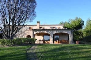 A brick building with arched doorways, a chimney, and a patio with outdoor furniture.