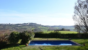 A swimming pool with a view of a hilly landscape and a distant town.