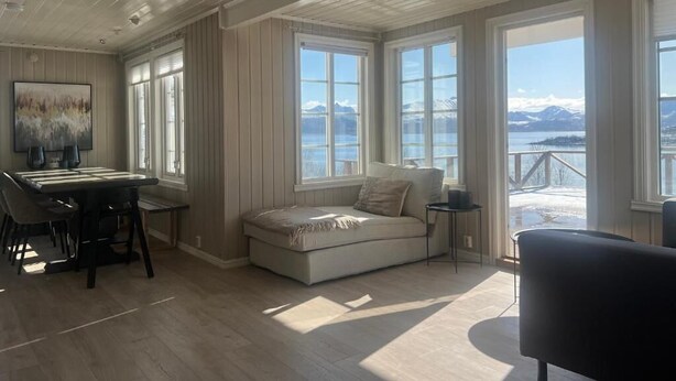 Una habitación amplia con un ventanal grande, un sofá, una mesa de comedor y vistas a montañas.