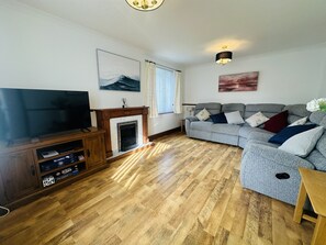 A living room with a television, fireplace, sofa, and wooden flooring.