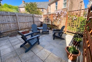 A patio with outdoor seating, a wooden fence, and potted plants.