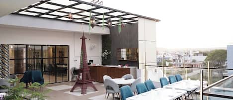 Een terras op het dak met een eethoek, een receptiebalie en een decoratief model van de Eiffeltoren.
