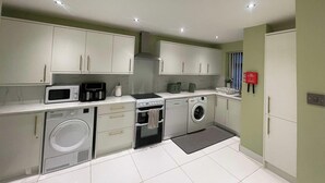 A compact kitchen with a microwave, coffee maker, oven, and washing machine. - House Sleeps 9 With Garden and Parking (Bradford)
