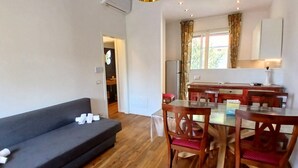 Ein Wohnzimmer mit einer Couch, einem Esstisch, Stühlen und einer Küchenzeile.