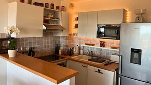 Cozinha moderna com micro-ondas, frigorífico, pia e bancada de madeira.
