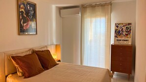 Quarto com uma cama, um quadro, uma luminária e um aparador.