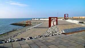 A coastal promenade with a paved walkway, a rocky shoreline, and a clear view of the sea. - “Apartment Amrum” in the heart of Büsum with balcony, centrally located and clos (Büsum)