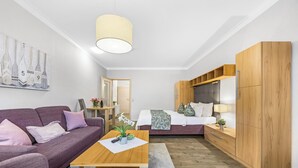 A modern hotel room with a sofa, a wooden coffee table, a bed with a headboard, a wardrobe, and a painting on the wall. - “Apartment Amrum” in the heart of Büsum with balcony, centrally located and clos (Büsum)