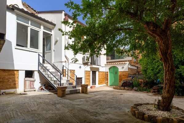 Un edificio con una escalera, una puerta verde y un árbol en el patio.