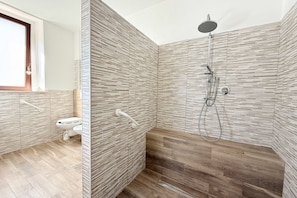 Une salle de bain moderne avec une douche, des toilettes et une fenêtre.