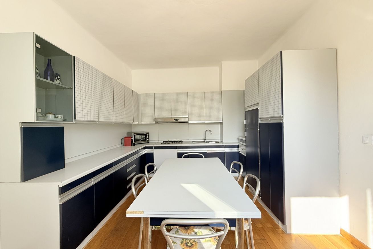 A compact kitchen with a dining table, cabinets, and a refrigerator.