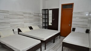 Quarto com três camas, um guarda-roupa e um espelho.