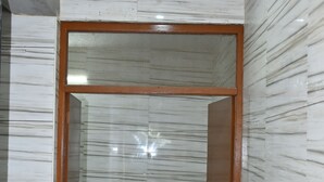 Quarto com parede de mármore, porta de madeira e chão xadrez.