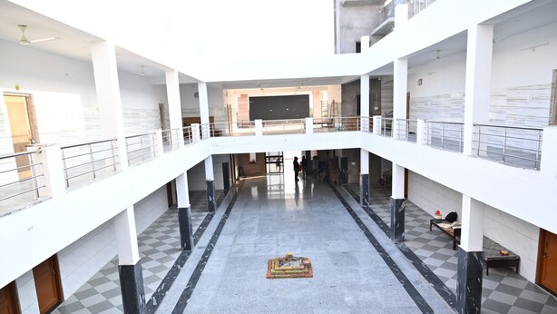 Um átrio em vários níveis com um espaço aberto central, guarda-corpos e um padrão de piso quadriculado.