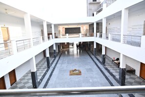 Un atrium à plusieurs niveaux, doté d’un espace central ouvert, de rampes et d’un motif de sol à carreaux.