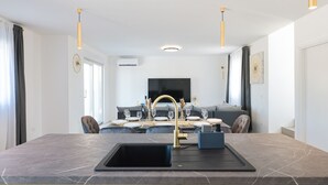 A modern kitchen with a marble countertop, a gold faucet, and a dining area with a sofa and table set for four. - Villa IviCasa with pool (Murvica)