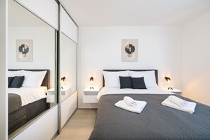 A modern hotel room with a large bed, bedside tables, wall art, and a mirror. - Villa IviCasa with pool (Murvica)