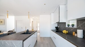 A modern kitchen with marble countertops, white cabinets, and pendant lighting. - Villa IviCasa with pool (Murvica)