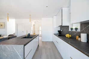 A modern kitchen with marble countertops, white cabinets, and pendant lighting. - Villa IviCasa with pool (Murvica)